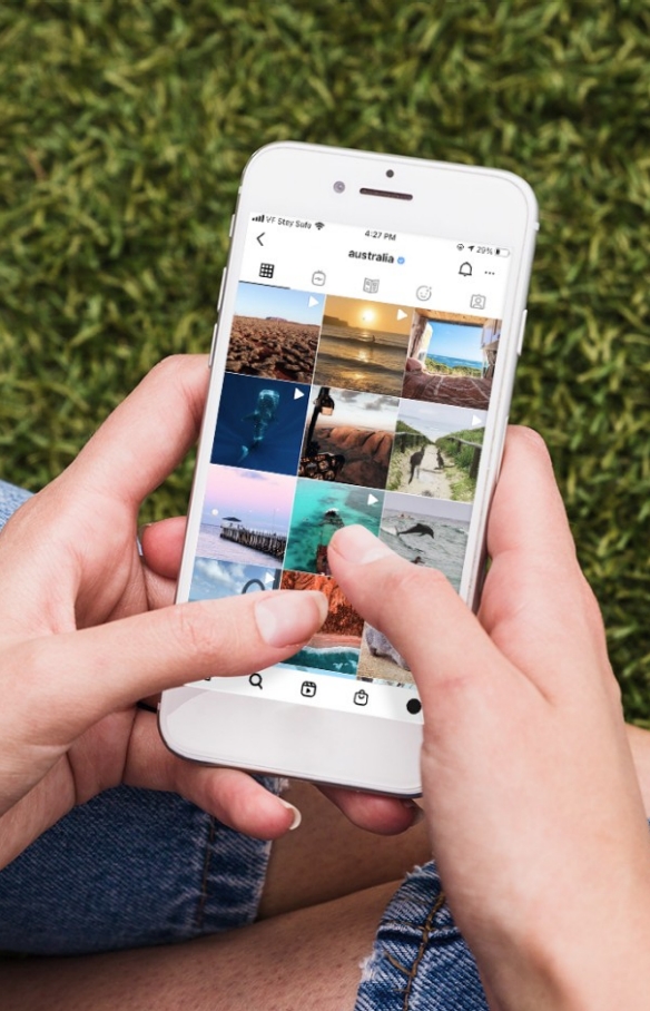Person sitting down with their mobile phone looking at Tourism Australia's Instagram account © Tourism Australia