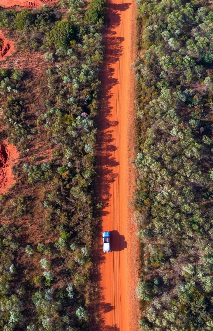 Aerial view of a car driving through the red dirt landscape of James Price Point in Kimbolton, Kimberley region, Western Australia © Tourism Australia
