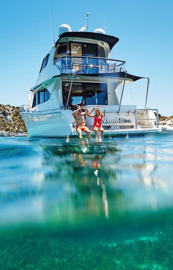 Couple sitting on the edge of a boat, Rottnest Island, Western Australia © Tourism Western Australia