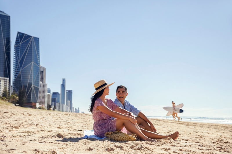 Couple sitting on the sand at Surfers Paradise Beach, Gold Coast, Queensland © Tourism and Events Queensland