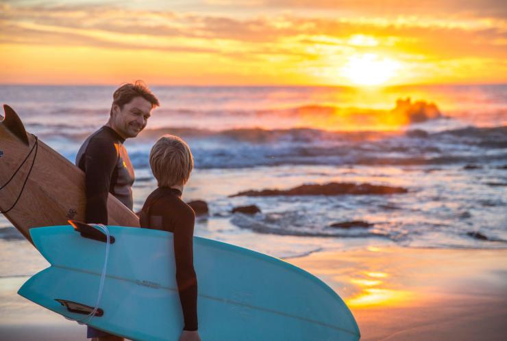 Father and son walking along the beacg at sunrise with their surfboards at Glasshouse Rocks, Narooma, New South Wales © Destination NSW Father and son walking along the beacg at sunrise with their surfboards at Glasshouse Rocks, Narooma, New South Wales © Destination NSW