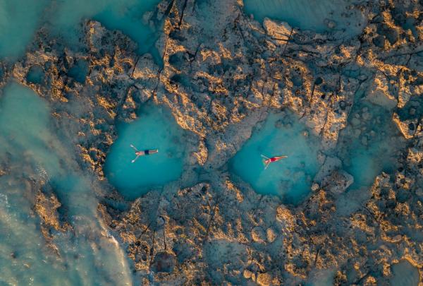 Aerial view of two people floating in their own rock pools on a very low tide near Gantheaume Point, Broome, Western Australia © Tourism Australia