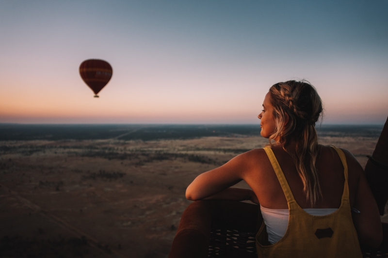 A visitor looks out over the Red Centre landscape while on a hot air balloon with Outback Ballooning © Tourism NT, Laura Bell